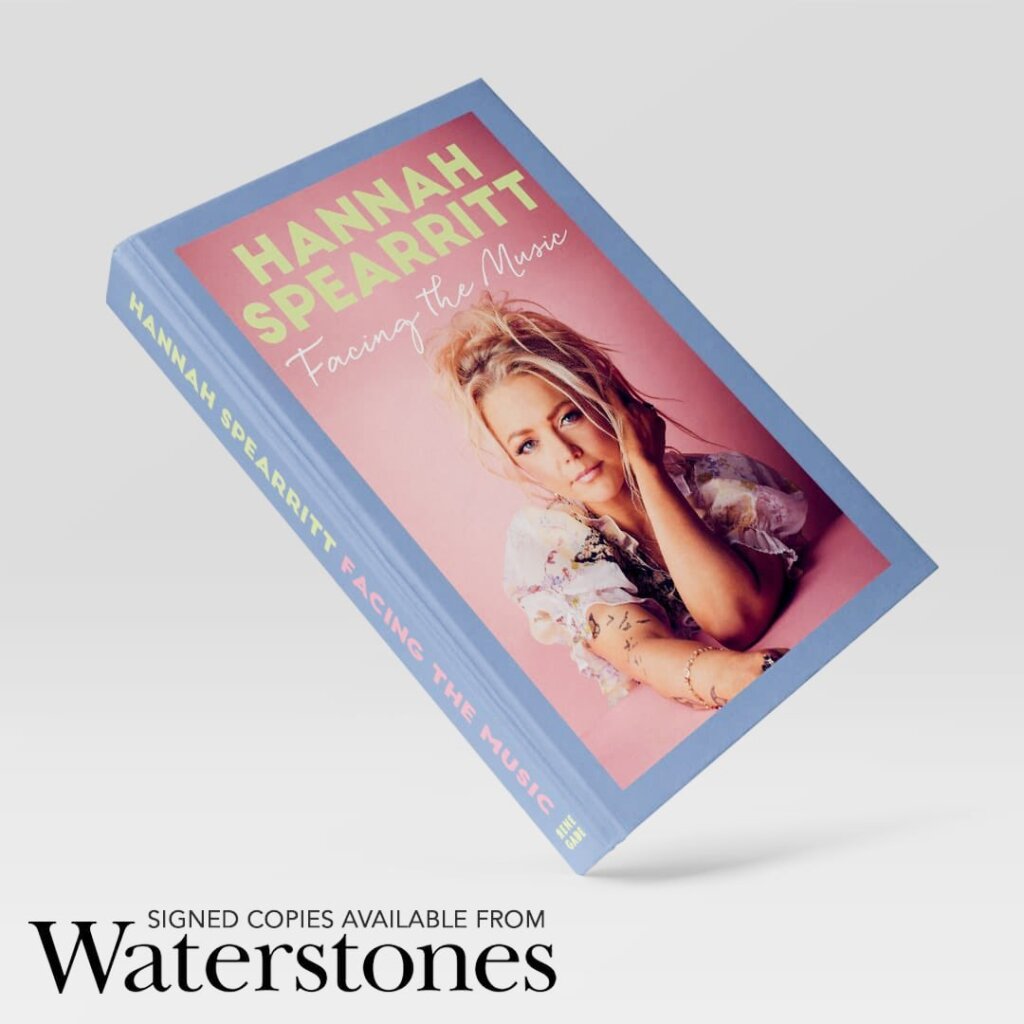 Hannah Spearritt's book "Facing The Music" positioned on a tilt with a white background. There's some writing in the bottom left announcing "Signed copies available from Waterstones".