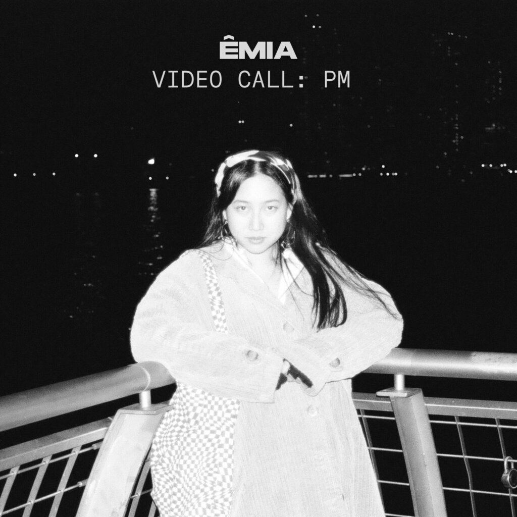 The EP artwork for "VIDEO CALL: PM" which sees a black and white image of ÊMIA leaning back into a railing on the side of the water. The exposure is turned all the way up and she looks almost ghostly.