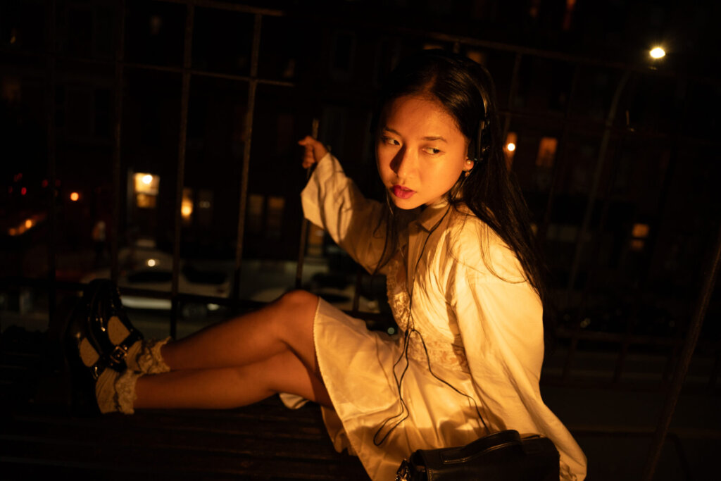 Promotional image for "VIDEO CALL: PM" which sees ÊMIA posing at night with the New York skyline behind her, on the floor.