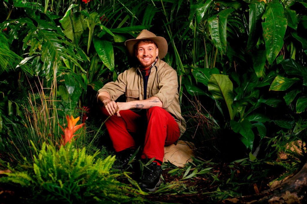 Promotional photo for I'm A Celebrity... Get Me Out Of Here! 2023, which sees Sam Thompson in a jungle setting, wearing the camp uniform.