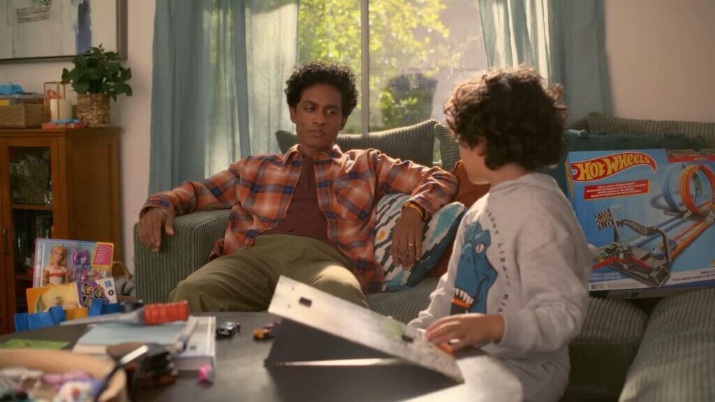 Still from Walmart's Mean Girls reunion advert which sees Rajiv Surendra talking to his son in the living room.