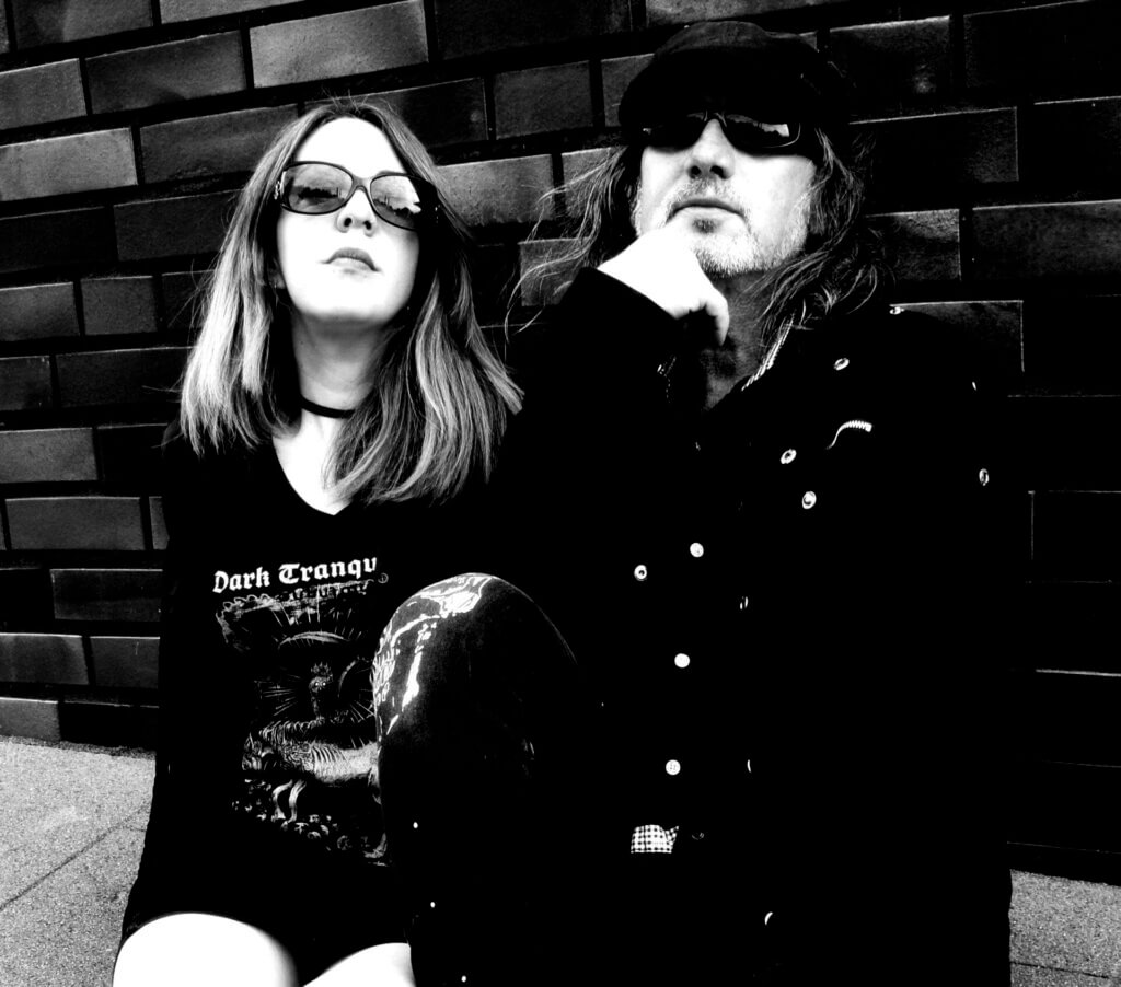Promotional photo of the metal duo Qarinah in black and white which sees Miss Randall sitting next to Waldemar Sorychta.