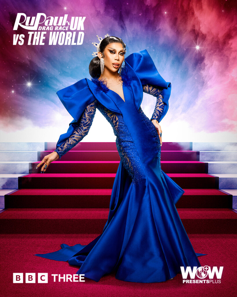 Marina Summers from RuPaul's Drag Race UK vs the World series 2, posing in a blue silk dress with a red carpet of stairs behind her.