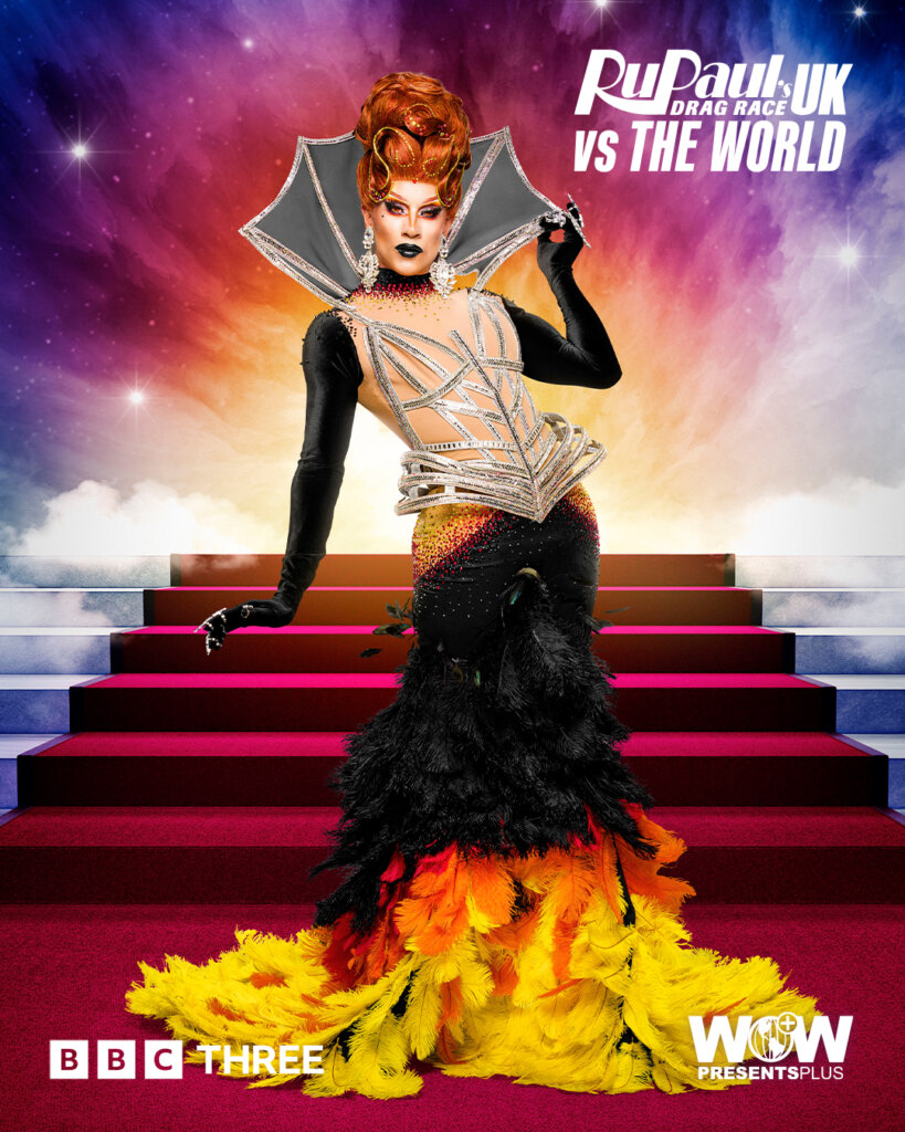 Kita Minaj from RuPaul's Drag Race UK vs the World series 2, posing in a black dress that imitates fire at the bottom of it paired with a jeweled corset and neck piece with a red carpet of stairs behind her.