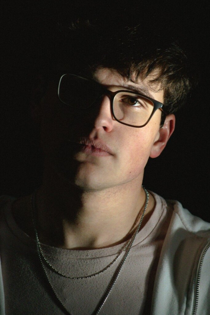 Promotional image for "Half of You" which sees a head shot of Rob Eberle, wearing black-rimmed glassed, two chain necklaces and a sweater.