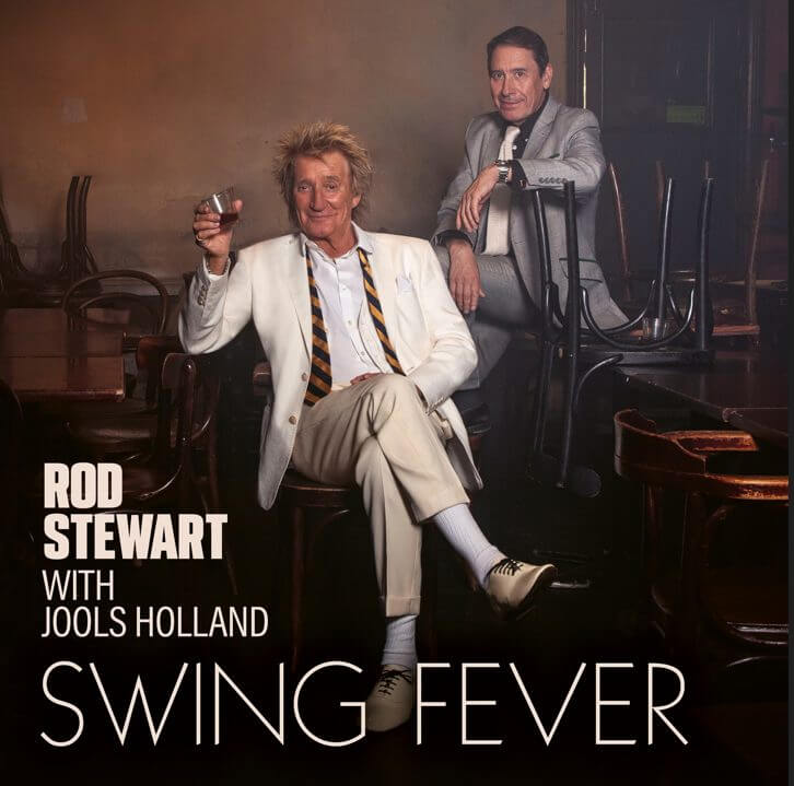 Album cover for "Swing Fever" which sees both Rod Stewart and Jools Holland sitting in a bar hall with Rod Stewart raising a glass as a toast.