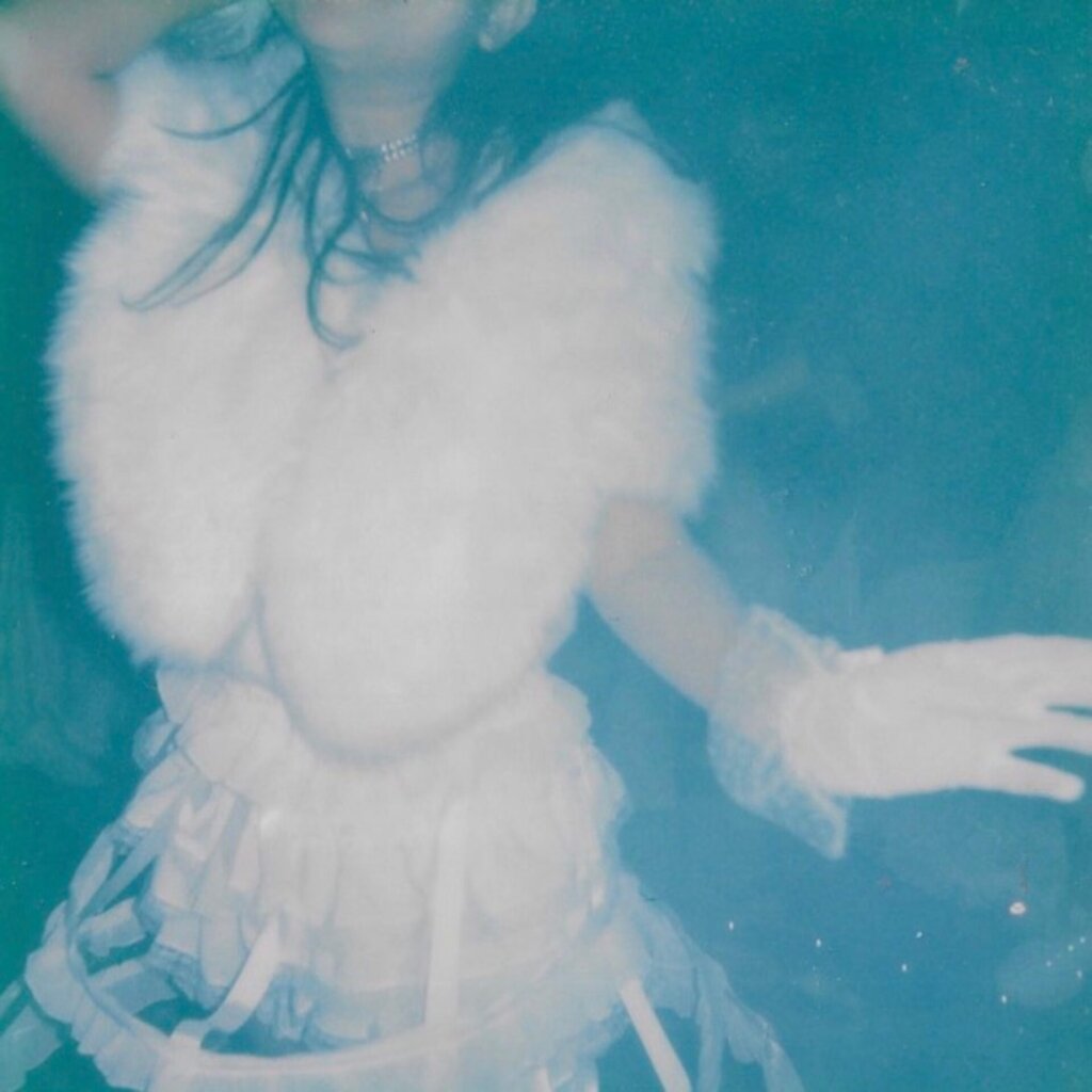 Official single cover artwork for "Super Fun Party Girl" which sees ÊMIA's torso showing a white dress with a white strap skirt. The image is filtered to a blue hue.