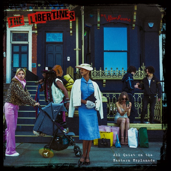 Official album artwork for The Libertines' album "All Quiet On The Eastern Esplanade" which shows a woman in a blue dress and a white cardigan that matches her hat, standing on a side street with various other women around her, from different walks of life.
