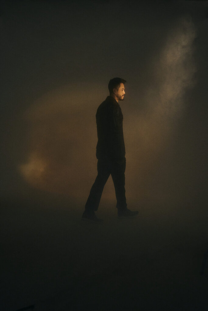 Promotional photo for "Dancing Lights" which sees Wils walking away in a light airy smoke as a subtle light can be seen from the top.