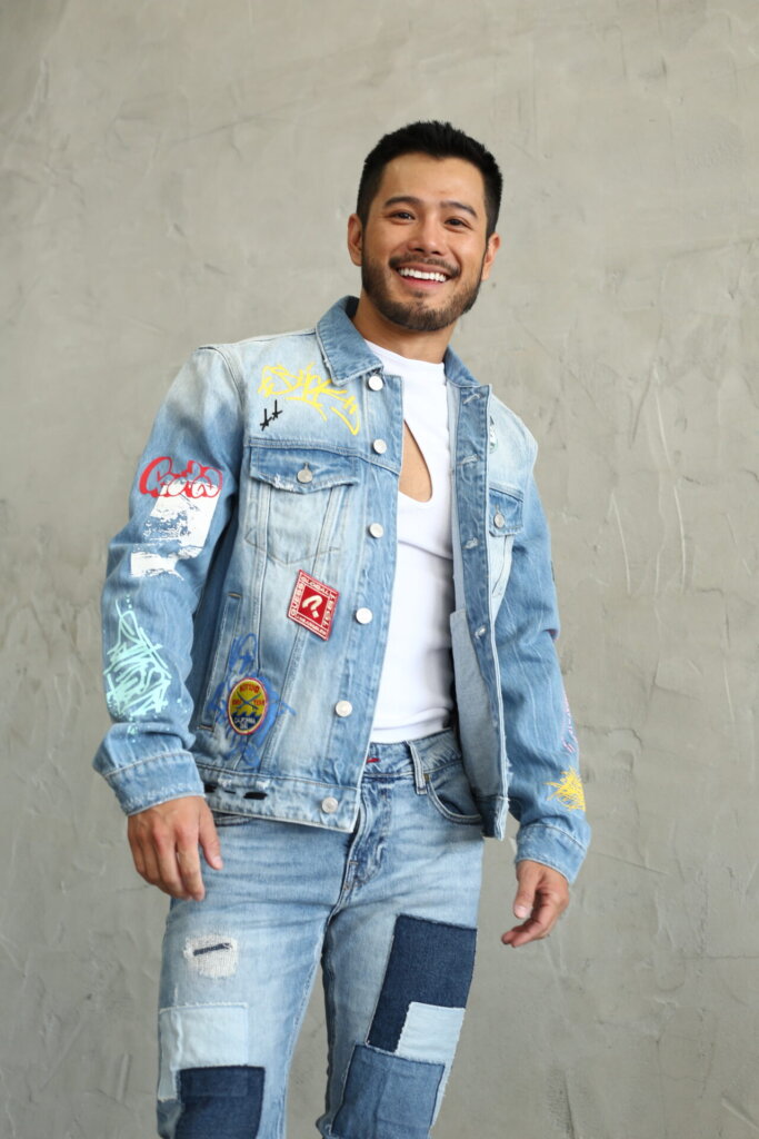 Full-length promotional photo for "Dancing Lights", which sees Wils smiling into the camera, wearing a blue denim jacket and a white t-shirt, with matching denim jeans.
