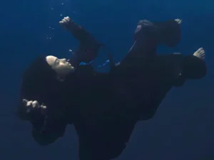 Cropped photo from the official album artwork of "HIT ME HARD AND SOFT" which sees Billie Eilish submerged in water breathing out bubbles.