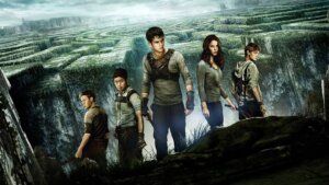 Film poster for The Maze Runner which sees the 5 main young adult characters standing on a cliff edge as the world opens up behind them.