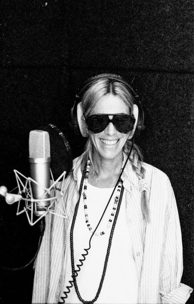 Black and white photo of Bird in the studio with headphones on, shades and standing in front of the microphone.