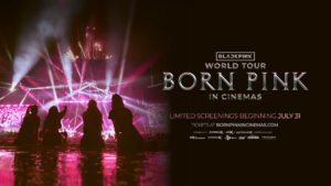 Official "BLACKPINK WORLD TOUR [BORN PINK] IN CINEMAS" film poster in landscape which sees the four-piece girl group BLACKPINK sitting on a stage, cast in shadow as spotlights beam down in front of them, lit up in pink. That's on the left side while on the right has the film's title and cinema release dates.