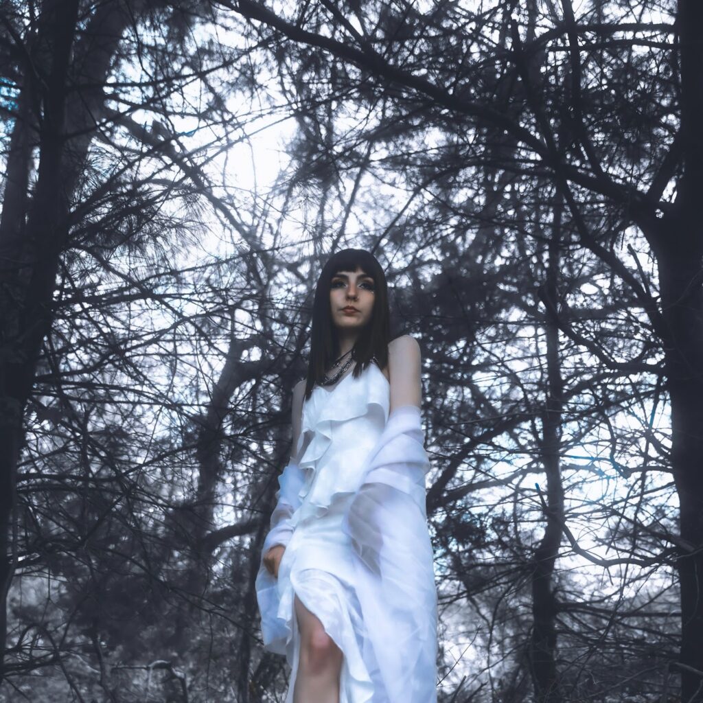Official single cover artwork for "Fading" which sees Calliope Wren wearing a white dress, walking amongst some trees.