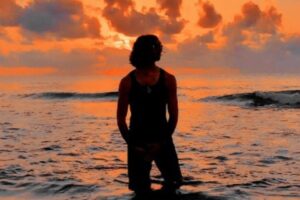 Image from the official artwork of "Sunburst" which sees Jesse Eplan standing in the water with the sun setting behind him.