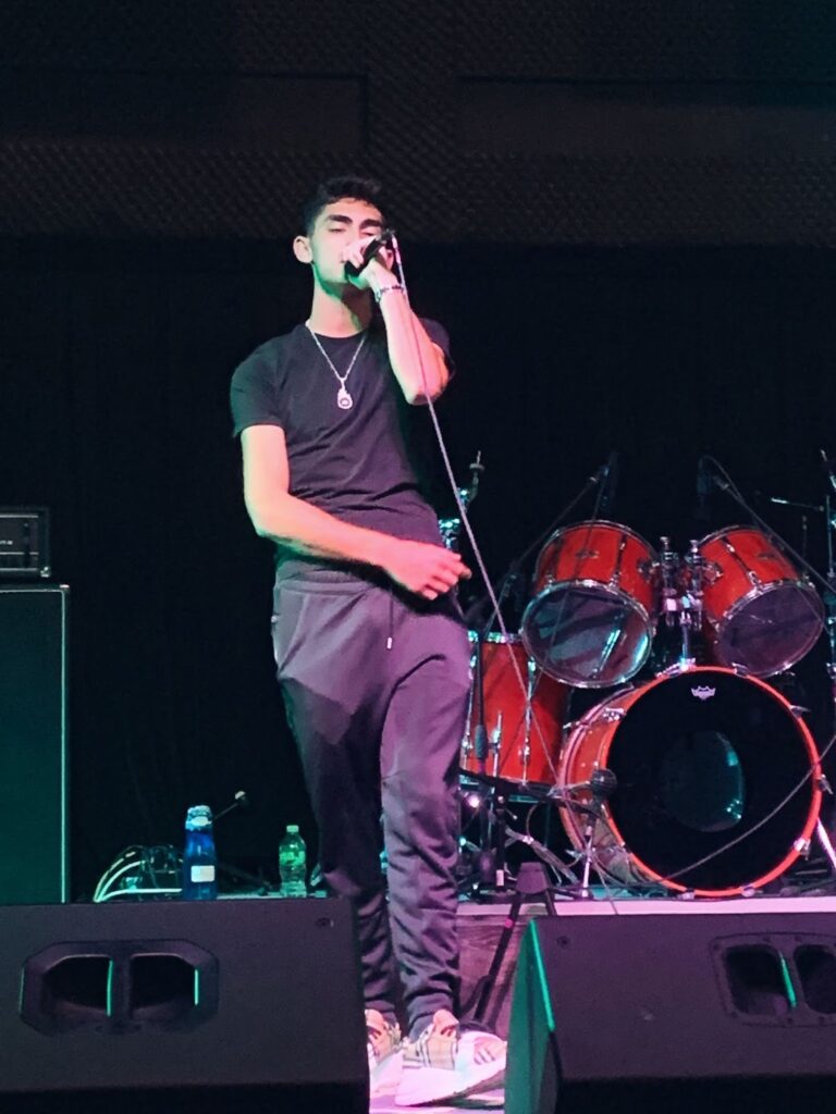 Jesse Eplan wearing trackies and a black shirt on stage performing one of his songs.