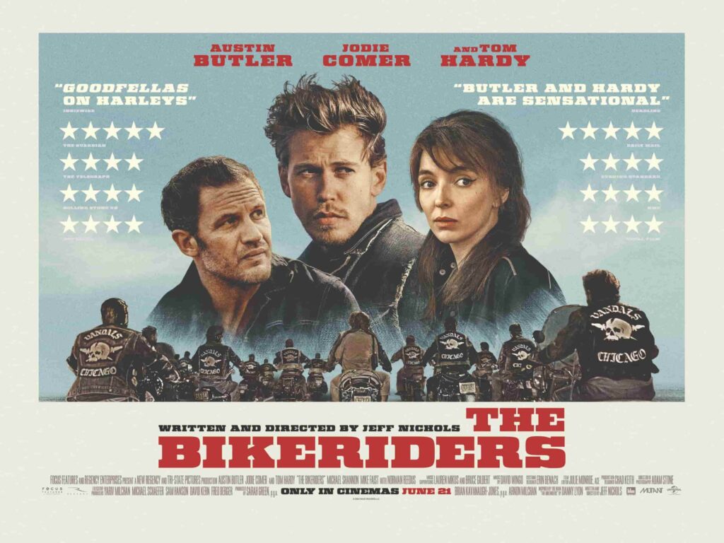 Official cinema landscape poster for The Bikeriders that sees the official photo of Tom Hardy, Austin Butler, and Jodie Comer with the row of motorcyclists riding, surrounded by a cream boarder and announcing the star ratings from magazines.