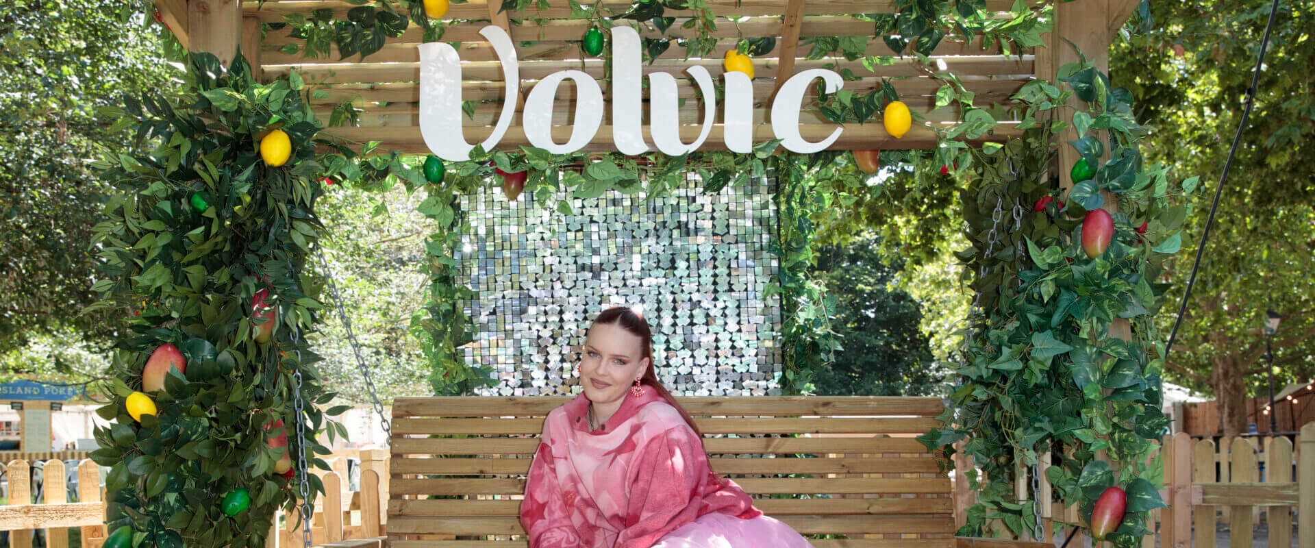 Anne-Marie posing in a pink flowing outfit on a garden swing in the Volvic HydeAway.