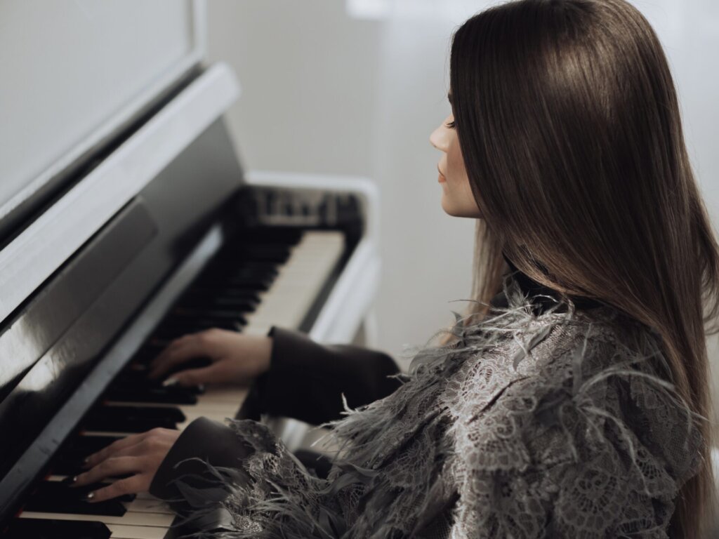 SOWA sitting at a piano with her hands on the keys.