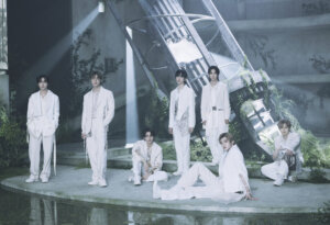 Photo of the seven-piece K-pop group NCT Dream on the set of the music video for "Rains in Heaven", which sees them all individually separated, wearing white, on a stage-like set with spotlights.