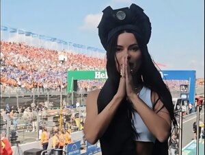 INNA arriving at the F1 Dutch Grand Prix to perform alongside Kris Kross Amsterdam. She's wearing a white crop vest and a black hat, and she has her hands together in a praying motion as her excitement builds.