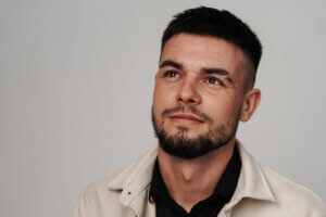 Headshot photo of Ігор Целип (Igor Tselyp) wearing a white jacket over a black shirt, looking forlonging past the camera.