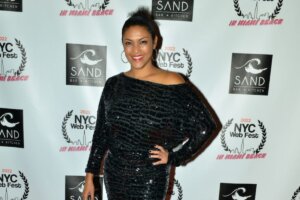 NYC Web Fest founder, Lauren Atkins, posing on the red carpet in a black sequinned dress, with one hand on her hip.