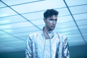 Promotional image for the "EVEN" music video which sees Stewart Taylor wearing a silver jacket over a white vest, with silver glitter under his eyes.