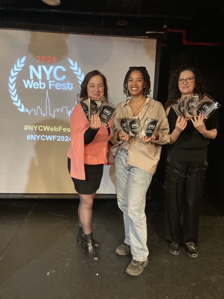 Marie-Hélène Lebeau Taschereau, Nadia Louis-Desmarchais and Marie-Élène Grégoire holding awards that their shows have won, in front of a screen with the NYC Web Fest 2024 logo on it.